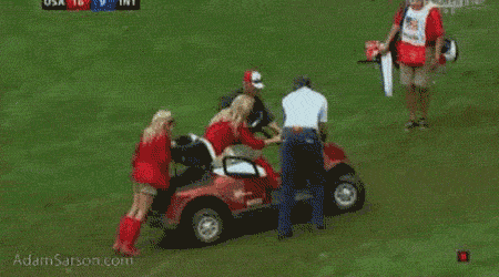 Amy Mickelson pushes golf cart out of the mud at the Presidents Cup